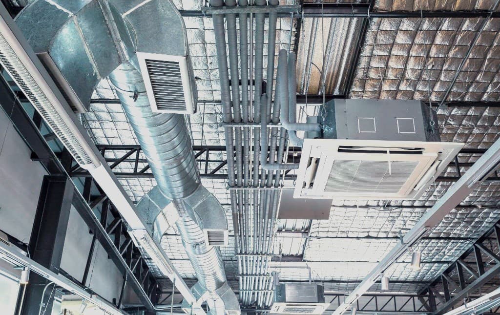 Techo industrial expuesto con conductos HVAC, tuberías y sistemas técnicos